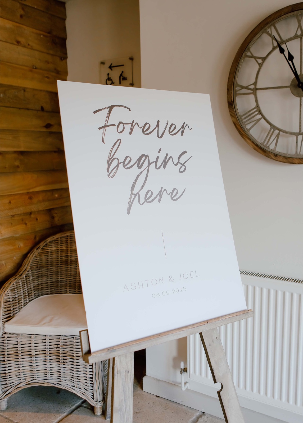 “Forever begins here” A1 wedding welcome sign on a wooden easel